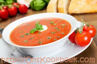 Romige tomatensoep met verse tomaten en basilicum, geserveerd in een kom
