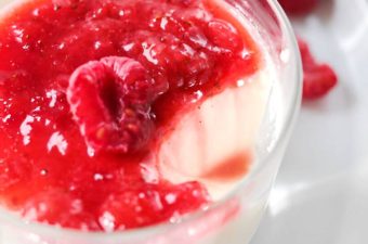 Romige vanille panna cotta in glaasje overgoten met fruitsausje