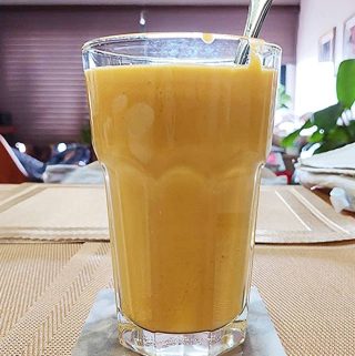 Mango lassi smoothie in glas met ijs, frisse drank bij warm weer