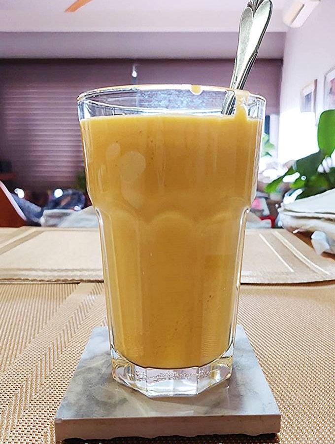 Mango lassi smoothie in glas met ijs, frisse drank bij warm weer