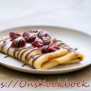 Opgerolde flensjes met verse aardbeien en chocoladesaus op een wit bord