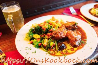 Konijn met pruimen en bier in Vlaamse saus, geserveerd met groenten en saus