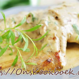 Konijnenbouten uit de oven onder een romige mosterdsaus, geserveerd met takje dragon op wit bord