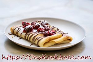 Opgerolde pannenkoek met verse aardbeien en chocoladesaus op een wit bord