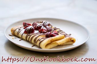 Opgerolde pannenkoek met verse aardbeien en chocoladesaus op een wit bord