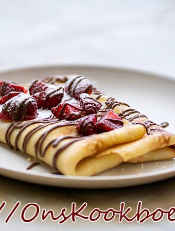 Opgerolde pannenkoek met verse aardbeien en chocoladesaus op een wit bord