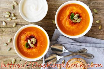 Romige pompoensoep met zoete aardappel en pompoenpitten, geserveerd met brood en crème fraîche