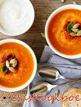 Romige pompoensoep met zoete aardappel en pompoenpitten, geserveerd met brood en crème fraîche