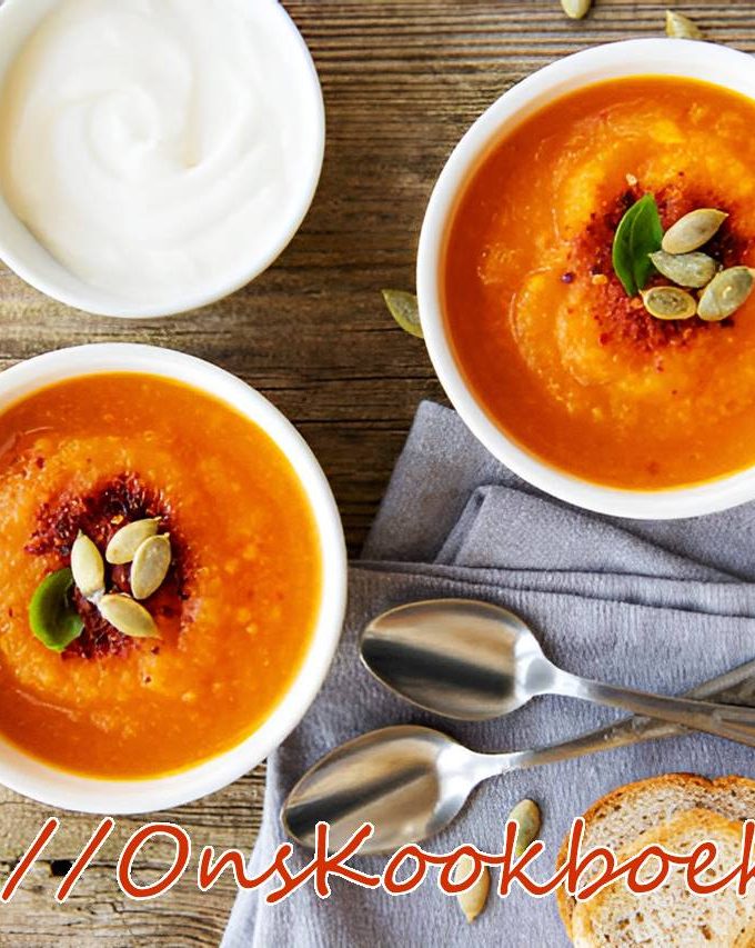 Romige pompoensoep met zoete aardappel en pompoenpitten, geserveerd met brood en crème fraîche