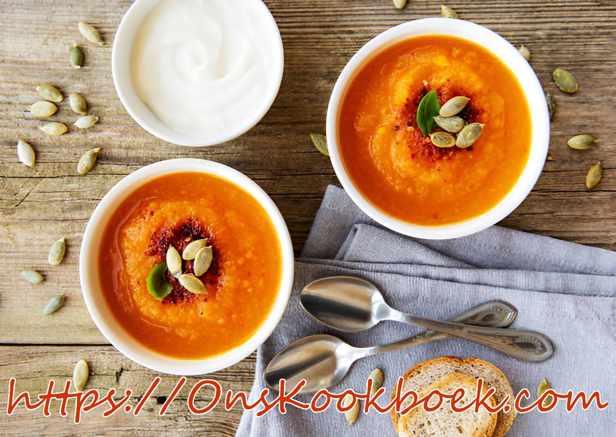 Romige pompoensoep met zoete aardappel en pompoenpitten, geserveerd met brood en crème fraîche