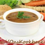 Witte soepkom met klassieke ossenstaartsoep, afgewerkt met peterselie op een rustieke tafel