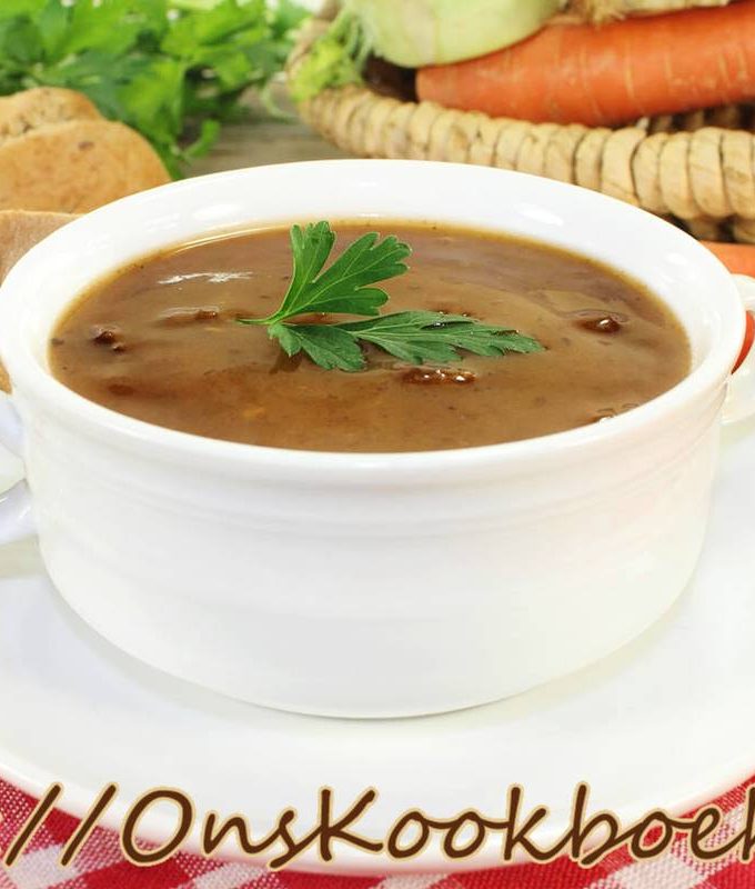 Witte soepkom met klassieke ossenstaartsoep, afgewerkt met peterselie op een rustieke tafel